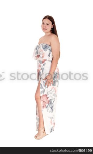 A beautiful young teenager girl standing in a gorgeous long summer dress in profile, looking at the camera, isolated for white background