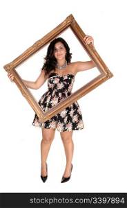 A beautiful young teenager in a nice dress holding up a golden old pictureframe, standing in the studio in high heels for white background.