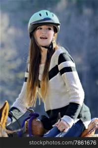 A beautiful young teenager on a horse looking back over her shoulder, she has braces on her teeth.