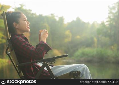 A beautiful young traveler woman is enjoying with nature drinking coffee in the morning over lake, relaxation , camping holiday and travel concept . . Beautiful young traveler woman is enjoying with nature drinking coffee in the morning over lake, relaxation , camping holiday and travel concept .