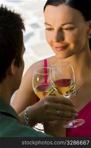 A beautiful young woman and her boyfriend toasting with glasses of white wine while bathed in summer sunshine