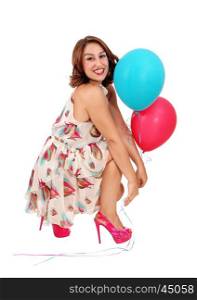 A beautiful young woman crouching on the floor holding two balloons, isolated for white background.