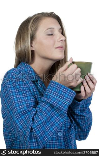 A beautiful young woman drinking and smelling coffee in her pajamas