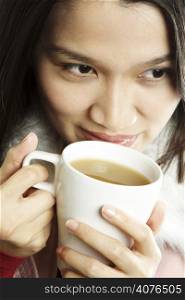 A beautiful young woman holding a cup of hot drink