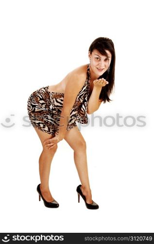 A beautiful young woman in a back free dress and brunette hair, highheels, bending forward and blowing a kiss, for white background.