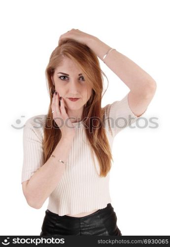 A beautiful young woman in a beige sweater and long brunette hairholding her hands on her face, isolated for white background