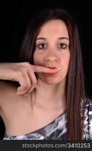 A beautiful young woman in a black and white dress standing in the studio with her finger in her mouths, for white background.