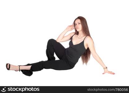 A beautiful young woman in a black outfit and long brunette hair sitting on the floor, hand on head, isolated for white background