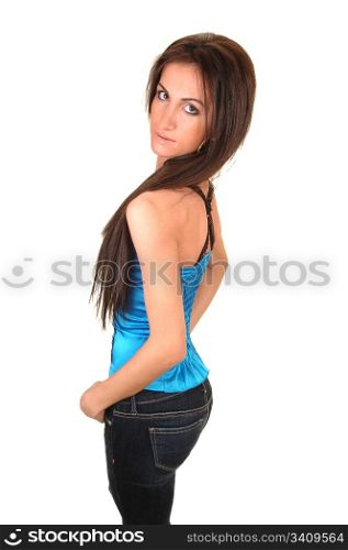 A beautiful young woman in a blue corset and jeans standing in the studio with her slim figure and long hair, for white background.