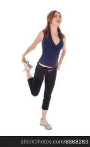 A beautiful young woman in a exercising outfit standing over whitebackground holding up her leg and stretching her body