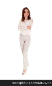 A beautiful young woman in a lace blouse and brunette hair standingin dress pants with arms crossed isolated for white background