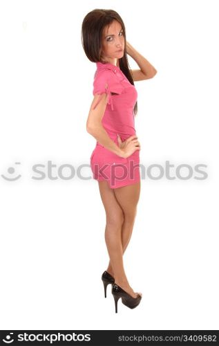 A beautiful young woman in a pink jumpsuit standing in the studio with herlegs crossed and looking into the camera, for white background.