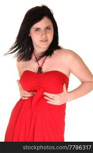 A beautiful young woman in a red dress standing in the studio and herblack hair is blowing away, for white background.