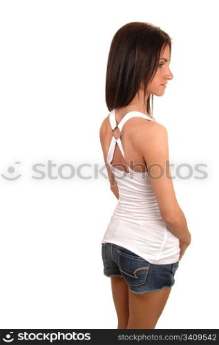 A beautiful young woman in a shorts and white top standing in the studio from the back, for white background.