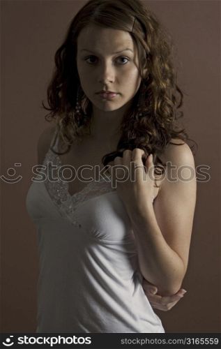 A beautiful young woman in a white top on a brown background