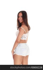A beautiful young woman in jeans shorts and small top standing fromthe back, looking over her shoulder, isolated for white background