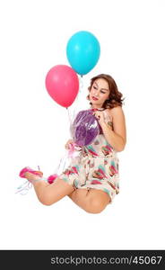 A beautiful young woman kneeling on the floor holding two balloons anda lollypop, isolated for white background.