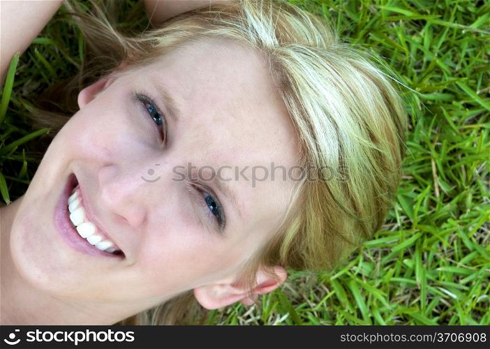 A beautiful young woman laying in a grassy yard. Sunset over a Lake