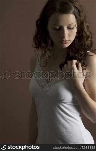 A beautiful young woman poses in front of brown background