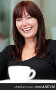 A beautiful young woman sitting in a cafe laughing