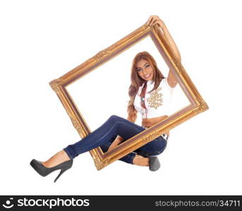 A beautiful young woman sitting in jeans with one leg trough a pictureframe, isolated for white background.