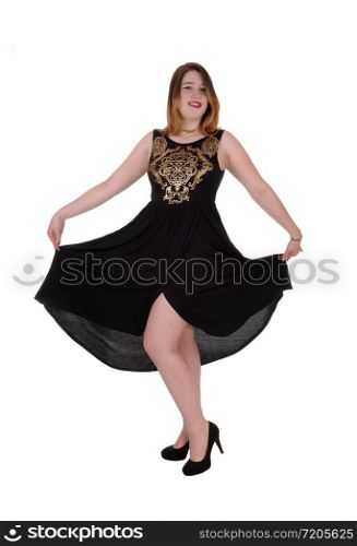 A beautiful young woman standing in a long black dress lifting up her dress, isolated for white background