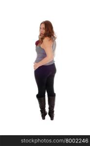 A beautiful young woman standing in black tights and boots from the backlooking over her shoulder, isolated for white background.