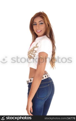 A beautiful young woman standing in profile in jeans and a white blousewith long brunette hair, isolated for white background.