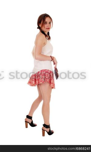 A beautiful young woman standing in profile, looking back, with a purse,standing isolated for over white background
