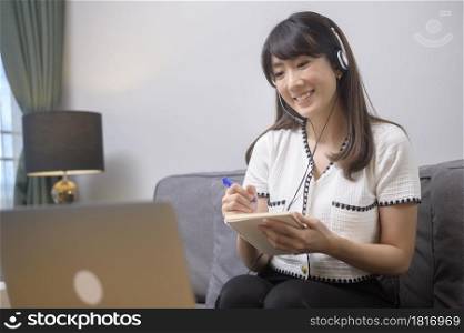 A beautiful young woman wearing headset is making video conference call via computer at home . Beautiful young woman wearing headset is making video conference call via computer at home