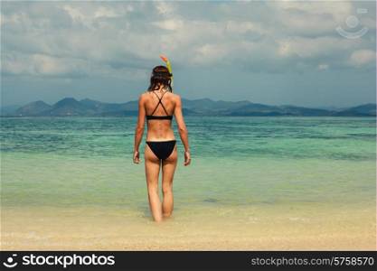 A beautiful young woman with a snorkel and diving mask on a tropical beach