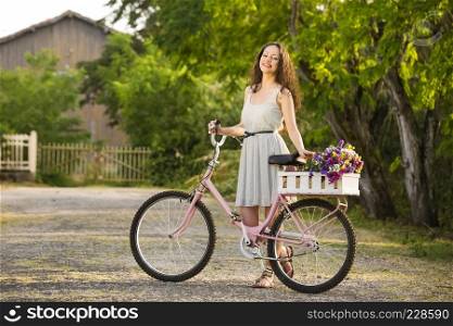 A beautiful young woman with her bicycle full of wildflowers 