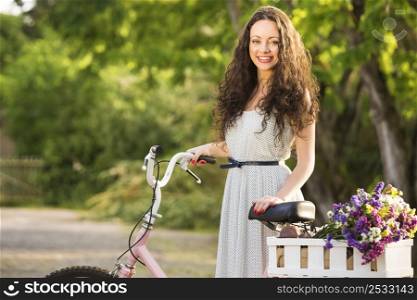 A beautiful young woman with her bicycle full of wildflowers