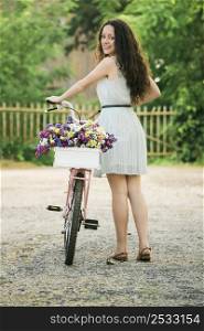 A beautiful young woman with her bicycle full of wildflowers