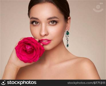 A beautiful young woman with shiny brunette hair. Girl with a rose flower. Model with healthy skin. Cosmetology, beauty and spa