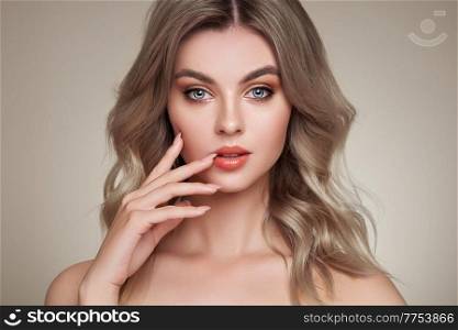 A beautiful young woman with shiny wavy blonde hair. Model with healthy skin, close up portrait. Cosmetology, beauty and spa