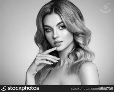 A beautiful young woman with shiny wavy blonde hair. Model with healthy skin, close up portrait. Cosmetology, beauty and spa. Fashionable black and white photography