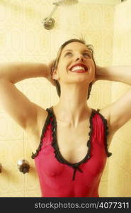 A beauty shot of a young 20s woman in the shower with water running over her face.