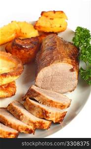 A beef &acute;eye roast&acute; joint, sliced into medallions, on a plate with roast potatoes and Yorkshire puddings.
