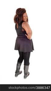A big African American woman in a black dress, tights and boots standingfrom the back isolated for white background.