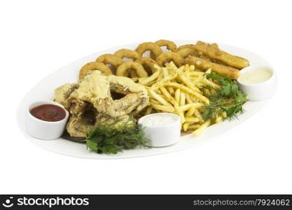 A big dish of chicken wings,onion rings,French fries and different sauces on an isolated background