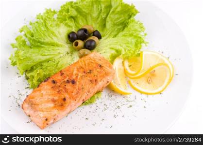 a big piece of grilled salmon, olives, lettuce and lemon