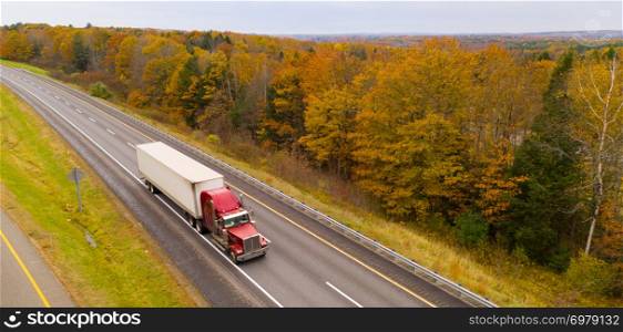 A big semi truck rig enjoys fall color in New England on the open road