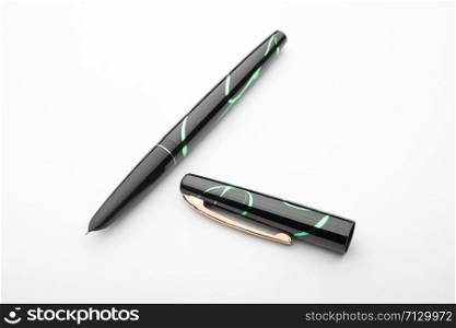 A black and green open fountain pen on a white sheet of paper