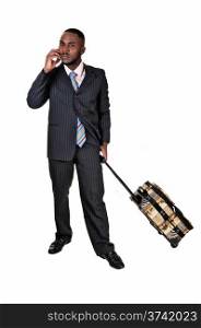 A black business man with his suitcase is standing for white backgroundin a blue suit and talking on the phone.