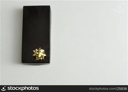 A black gift box with a gold bow isolated on a white background