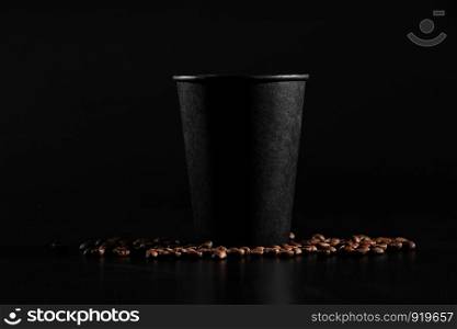 a black glass of coffee. Coffee is scattered on a dark background.. a black glass of coffee. Coffee is scattered on a dark background. side view