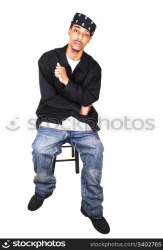 A black man in jeans, way down, and very big and long shirt, with a headscarf,sitting in the studio, for light blue background.