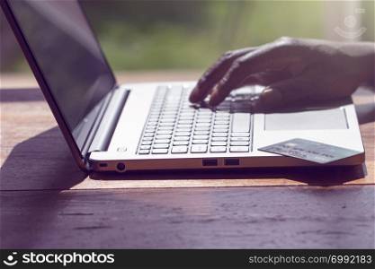 A black person conducting an online transaction with laptop and credit card