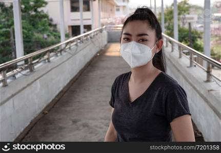 A Black shirt woman standing on putting on a respirator N95 mask to protect from airborne respiratory diseases as the flu covid-19 coronavirus PM2.5 dust and smog on the road burred background